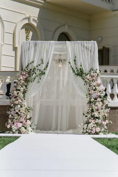 O arco quadrado é decorado com lustre elegante, véu branco e grandes composições de flores frescas nas laterais — Fotografia de Stock