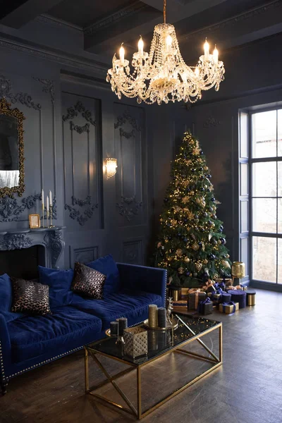 New Year\'s decor and atmosphere in a large living room with dark walls. Christmas tree. Stylish modern living room