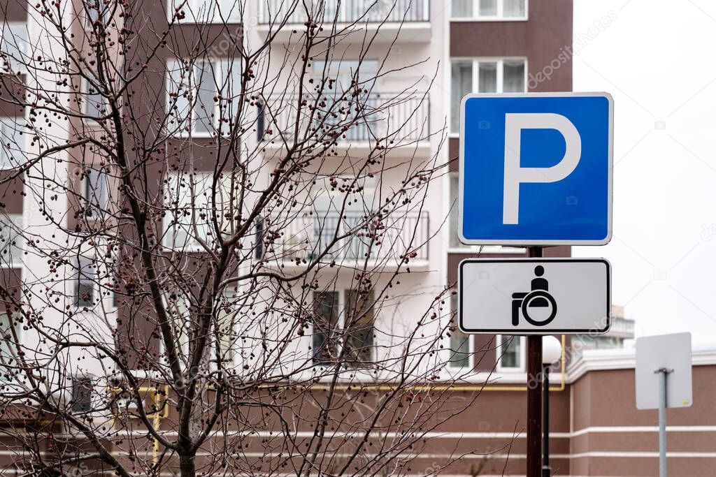 Traffic sign parking space for wheelchair users and disabled drivers in redidential area. Blue fill with white text. Capital letter P and carriage sign for disabled people