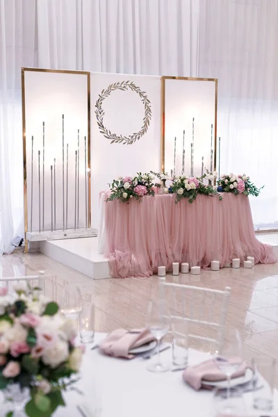 The luxurious round table for the wedding lunch is decorated with flowers and stylish dishes.