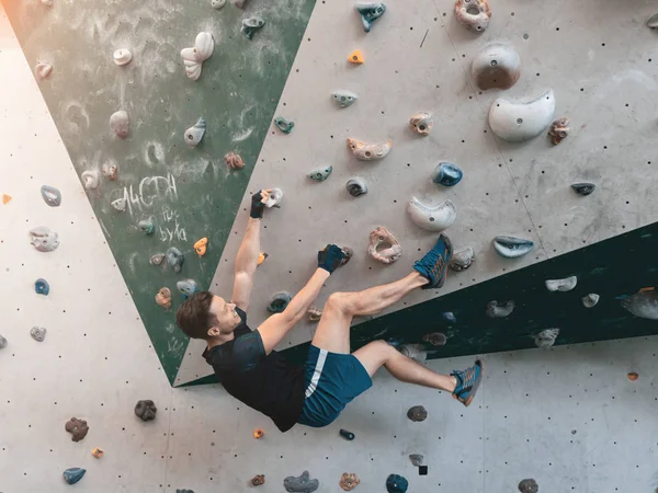 En man klättrar i stenblock gym i väggen. — Stockfoto