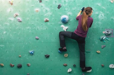 Duvardaki kaya spor salonuna tırmanan bir kadın..