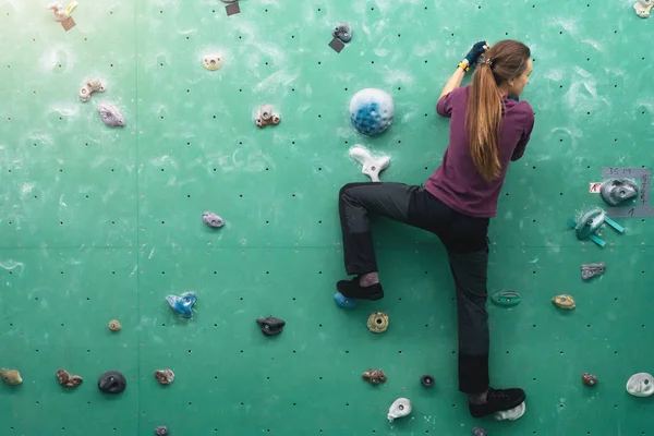 Een vrouw klimmend in de kei gym in de muur. — Stockfoto