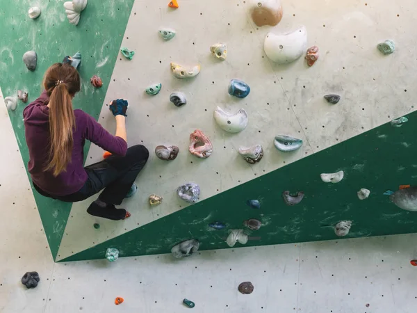 Een vrouw klimmend in de kei gym in de muur. — Stockfoto