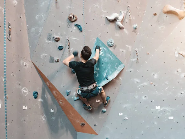 Een man klimmend in de kei gym in de muur. — Stockfoto