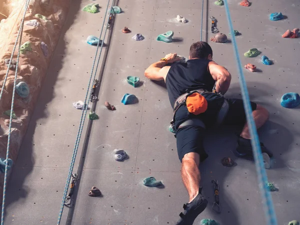 Een man klimmend in de kei gym in de muur. — Stockfoto