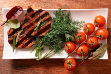 Ahşap arka planda sebze ve biftek.