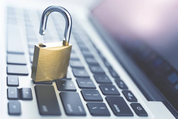 Computer security concept. Unlocked padlock on laptop keyboard. Symbol of safe. Toned soft focus picture.