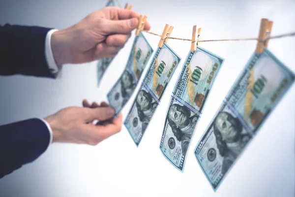 Het wassen van geld concept. Zakenman wast geld wit, 100 dollar biljetten hangen aan een waslijn. Symbool van witwassen van geld. Zachte focus. — Stockfoto