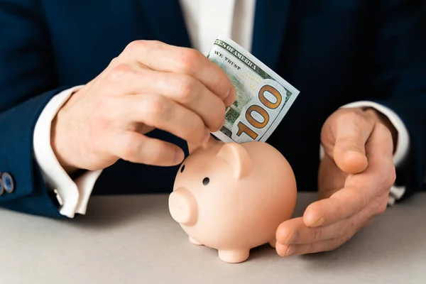 Money Protecting concept. Saving symbol - Close-up Of A Human Hand puts a 100 dollar bill in Pink Piggy Bank — Stock Photo, Image