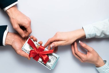 Konsept, para hediye olarak, kazanmak ya da ikramiye olarak. İş adamı, kırmızı kurdeleyle bağlanmış 100 dolarlık banknotları alır ya da verir. Düz görünüm kopyalama alanı.