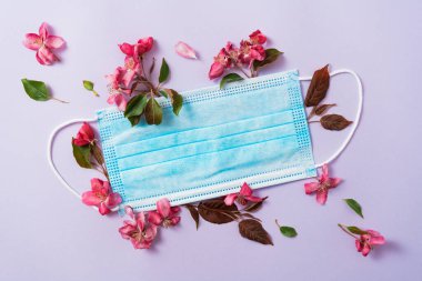 Coronavirus zafer konsepti. Anti-virüs tıbbi maskesi ve bahar kırmızı çiçekleri. COVID-19 salgın sembolünü durdurun. Virüs fikrini yok etmek. Üst görünüm kopyalama alanı, düz yatay.