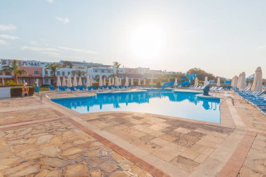Güneş şezlongları ve saman şemsiyeli alçak mevsim boş plajlar. Girit şehrinde Hersonissos Günü fotoğrafı. Yunanistan tatili.