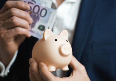 Para koruma konsepti. Tasarruf sembolü - İnsan elinin yakın çekimi Pembe Piggy Bank 'a 500 euro yatırdı