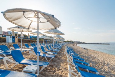 Low season empty beach with sun loungers and straw umbrellas. in Crete town Hersonissos Day foto. Greece vacation. clipart