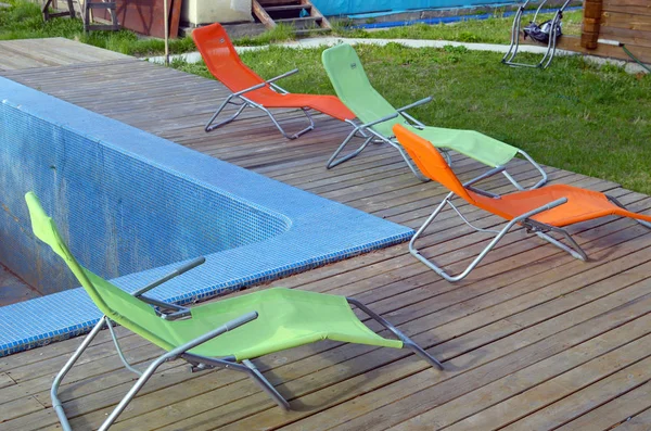 Cuatro chaise-longues están en la piscina vacía en un día nublado —  Fotos de Stock