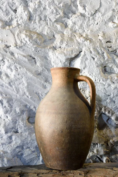 Clay jug on shelf against background of old stone wall — Stock Photo, Image