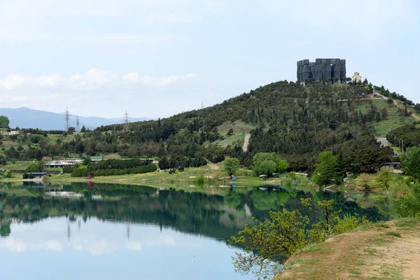 Suprafața netedă a rezervorului Tbilisi apă și deal cu monumentul Cronici ale Georgiei dimineața — Fotografie de stoc gratuită