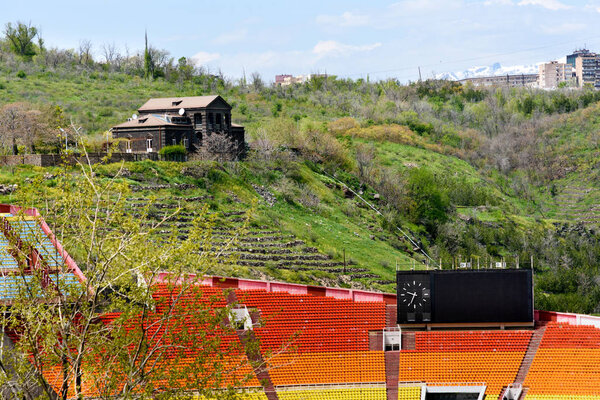 The stands of Hrazdan Stadium and house on hill.