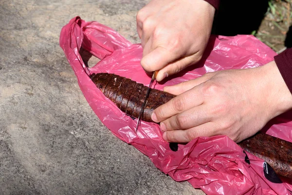 Las manos de los hombres cortan sujuk en la bolsa de plástico usada para merienda — Foto de Stock