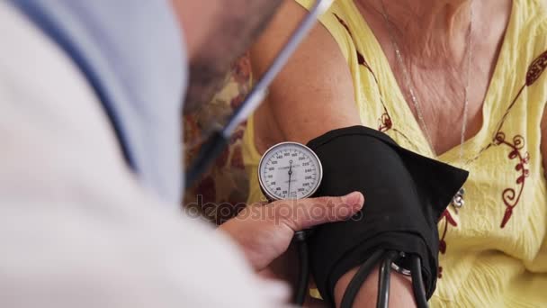 Člověk pracující v hospicové a měření krevního tlaku ženy