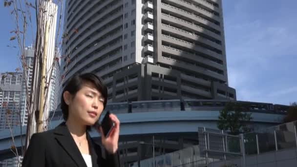 Bella donna asiatica che parla sul telefono cellulare vicino agli edifici degli uffici — Video Stock