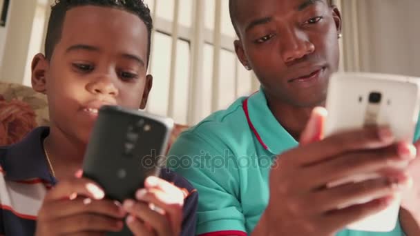 Joven hombre explicando el Internet del teléfono móvil al niño en casa — Vídeo de stock