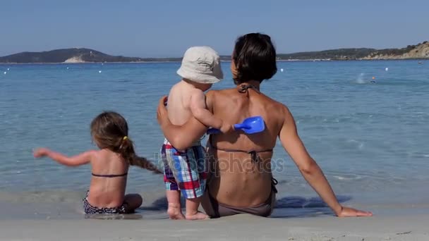 Счастливая семья, играющая на пляже у моря — стоковое видео