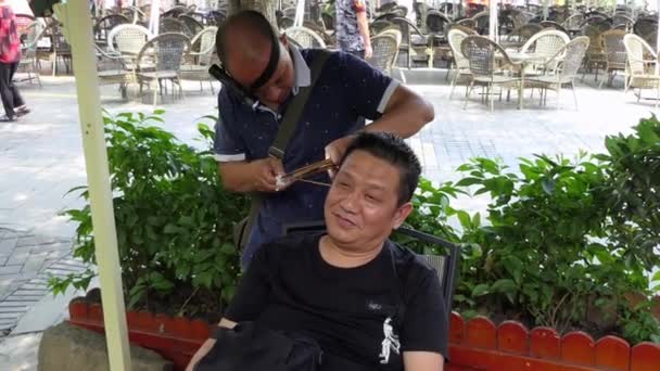 Homem praticando a remoção de cera de limpeza de ouvido tradicional na China Ásia — Vídeo de Stock