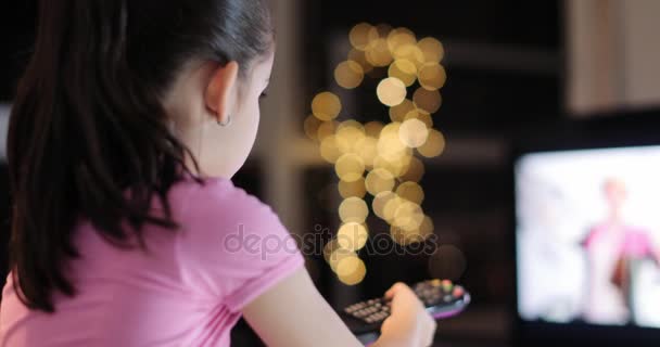 Молода дівчина дивиться телевізор самотужки без батьківського контролю — стокове відео