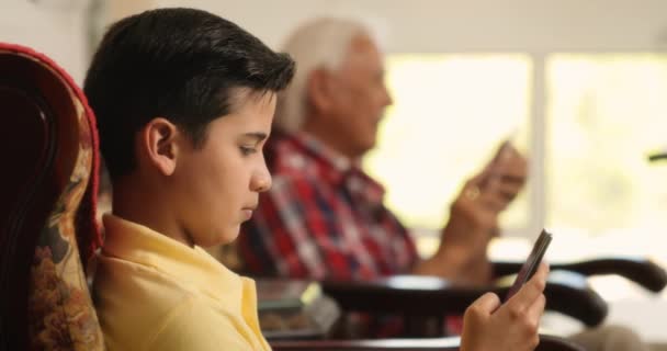 Дедушка и внук используют мобильный телефон для интернета — стоковое видео