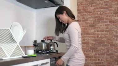 Genç Asyalı kadın evde yemek pişirme. Güzel Japon kız yerli mutfakta yemek hazırlanıyor. Bir ev kadını olarak çalışan meşgul kişi