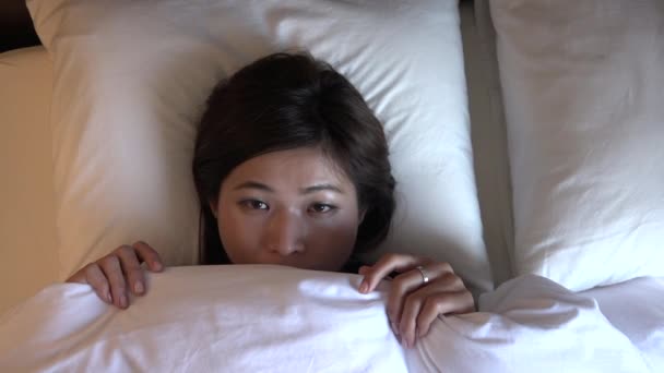カメラに笑顔幸せなアジアの女の子の肖像画 日本の若い女性は自宅に毛布にくるまって笑みを浮かべて顔を表示 ベッドのシーツを引っ張る人 スローモーション — ストック動画
