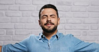 Genç sakallı adam tuğla duvar yüz ifadeleri