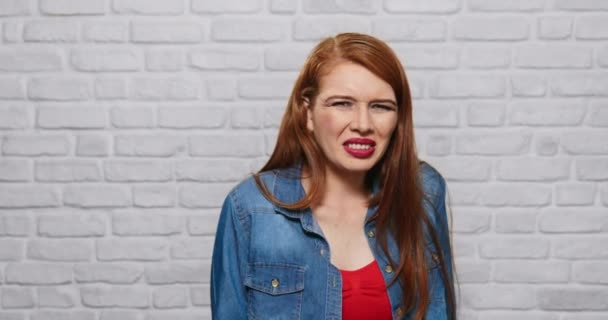 レンガの壁の若い赤毛の女性の表情 — ストック動画