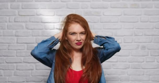 Вирази обличчя молодої рудоволоса жінка на цегляній стіні — стокове відео