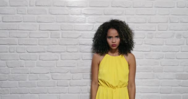 Выражение лица молодой чёрной женщины на кирпичной стене — стоковое видео
