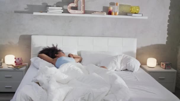Прекрасная молодая афроамериканка просыпается в постели — стоковое видео