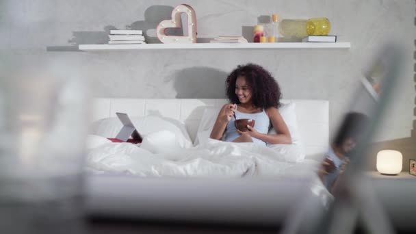 Adolescente comer café da manhã assistindo Comedy Show na cama — Vídeo de Stock