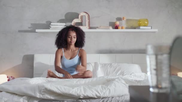 Jeune femme afro-américaine faisant du yoga au lit après le sommeil — Video