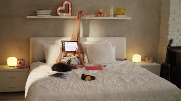 Mujer estudiando en la cama haciendo tareas al atardecer — Vídeo de stock
