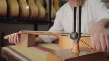 Müzik laboratuarında Lutemaker iş yerinde ve gitarı akort ediyor.