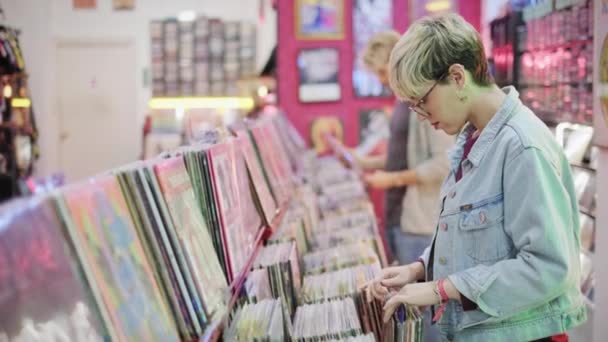 Молодая женщина выбрала винтажный винил LP в магазине Records — стоковое видео