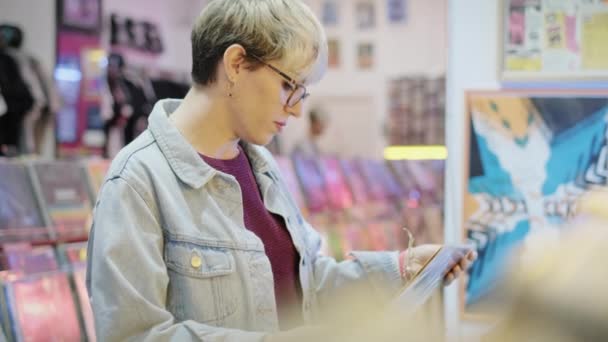 Junge Frau wählt Vinyl-LP im Plattenladen — Stockvideo