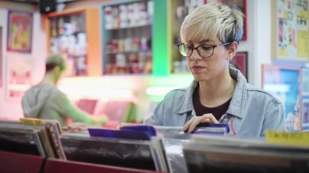 Молода жінка вибирає старовинні вінілові LP в магазині рекордів — стокове відео