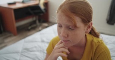 Evdeki yatak odasında küçük üzgün bir kıza sataştılar. Yalnız kızıl saçlı kadın çocuk yatakta oturuyor. Duyguları, üzüntüsü ve yalnızlığı var.