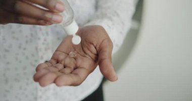 Karantina sırasında sıvı el dezenfektanı kullanan bir zenci kadın. Alkol bazlı jel kullanan Afrika kökenli Amerikalı kız el derisini virüslere, mikroplara ve bakterilere karşı dezenfekte ediyor.