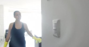 Evdeki elektrik ve elektrik düğmelerini silen kadının yakın görüntüsü. İnsanlar virüsleri ve mikropları öldürmek için iç yüzeyleri temizleyip dezenfekte ediyorlar. Ev hanımı işi ve ev işleri