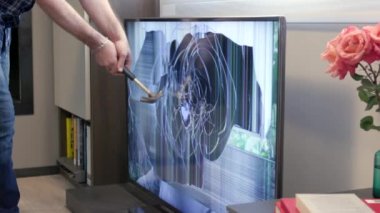 Çılgın adam çekiçle LCD TV setini parçalıyor. Deli insanlar öfke ve şiddet araçlarıyla televizyon monitörüne vuruyor. Yavaş çekim