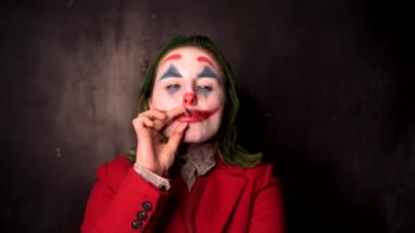 Cadılar Bayramı makyajı: siyah arkaplanda sigara içen kadın joker makyajı